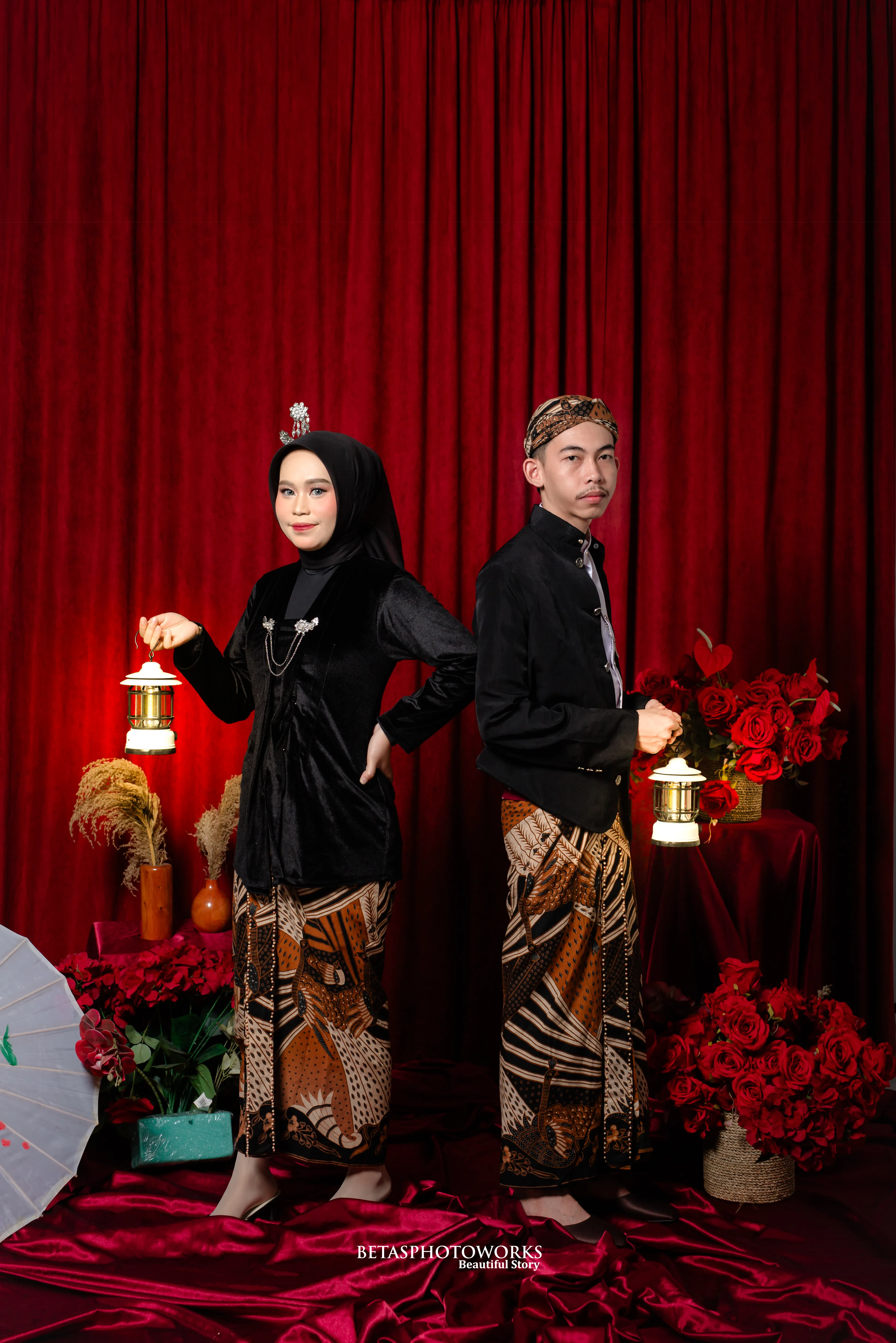 Tiara dan Roni membawa lentera di depan tirai merah